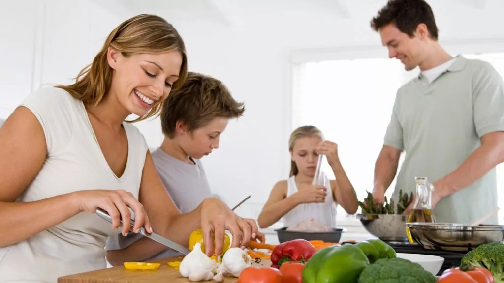 Family of four preparing to cook dinner in the kitchen a daily activity that adds moisture to the air.